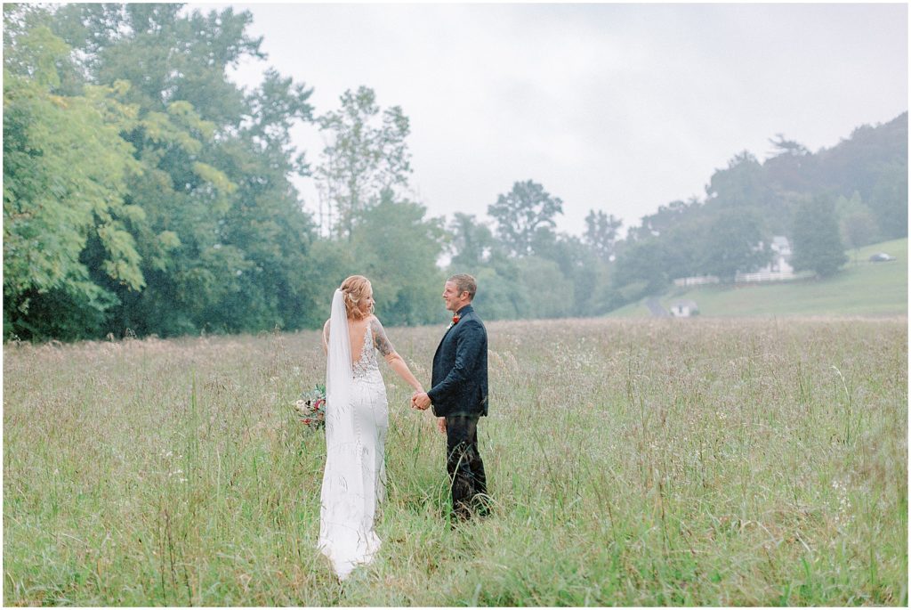 Rainy Virginia Wedding bride and groom walking in a field