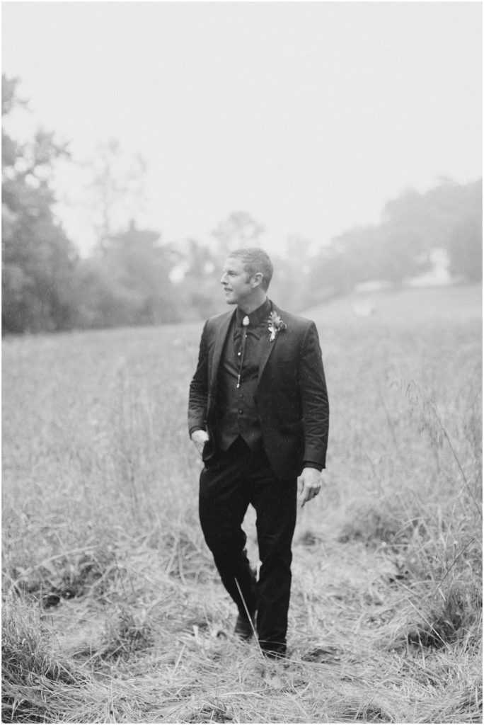 Virginia wedding groom walking in a field in the rain