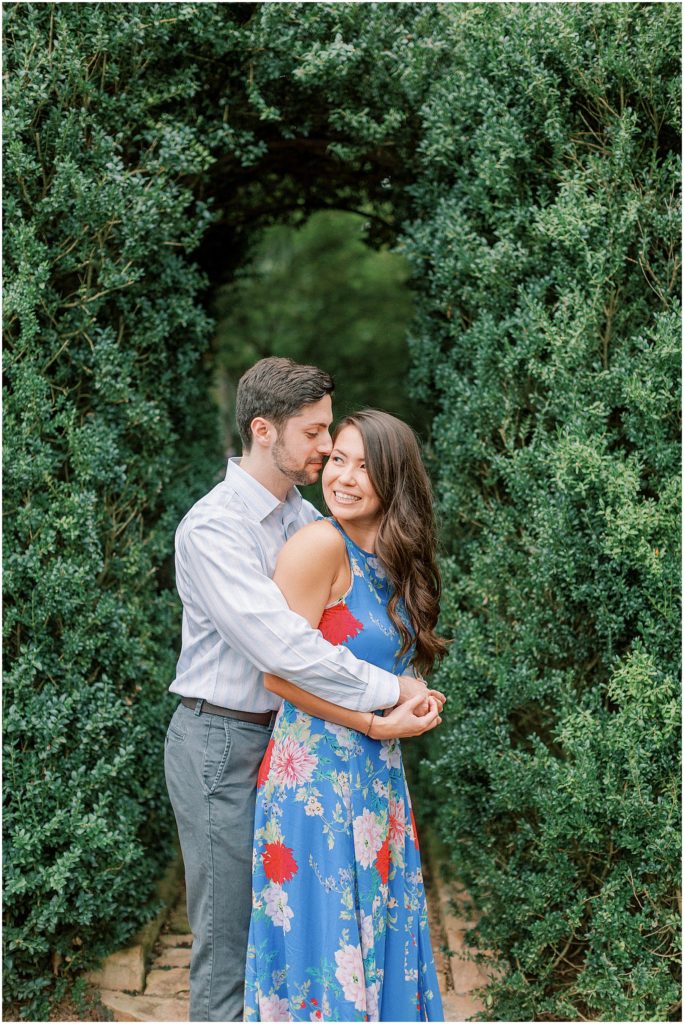Couple snuggling in garden during engagement session