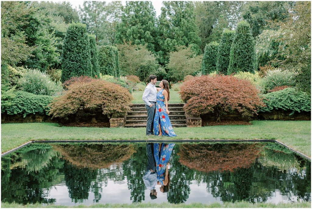 couple standing together during engagement session by a reflective pond