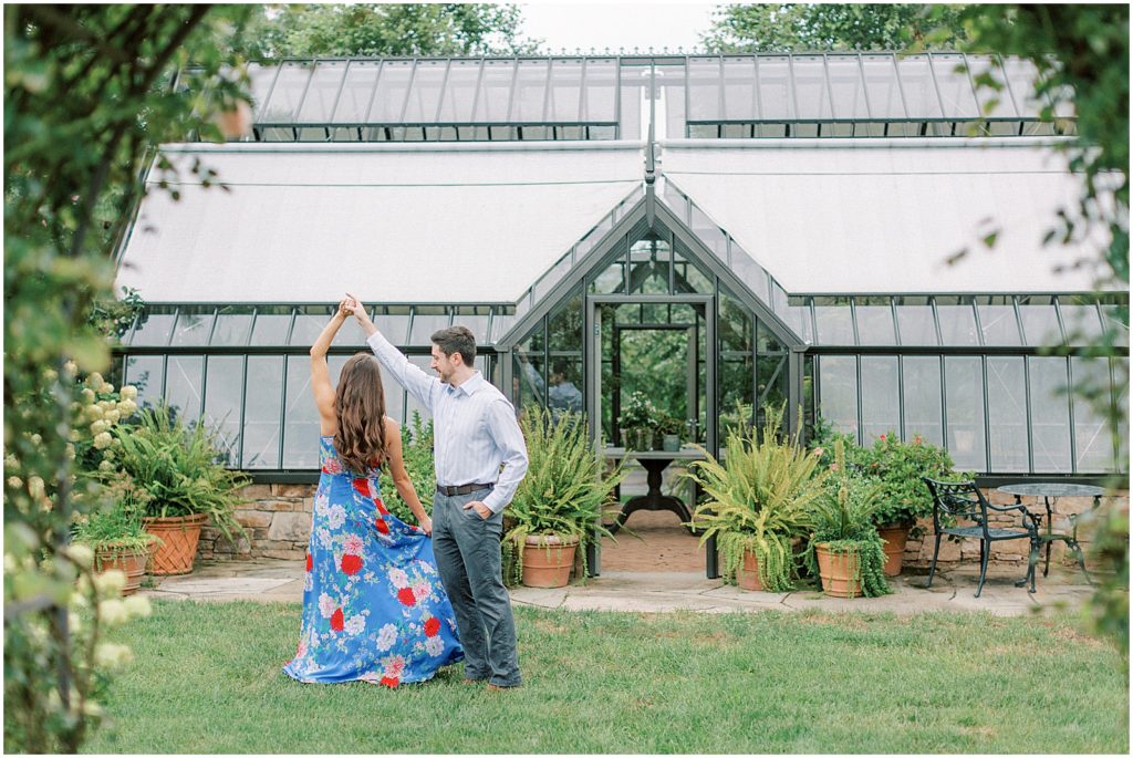couple dancing by a greenhouse during engagement session