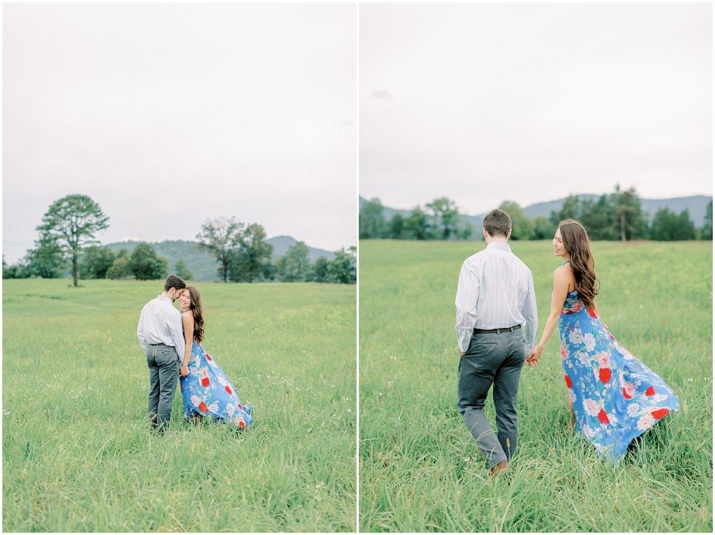 couple walking away in a field holding hands during engagement session