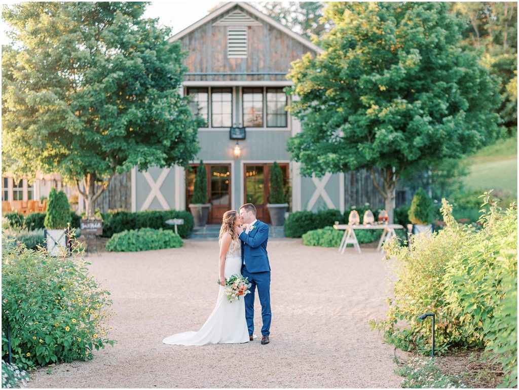 Bride & Groom kissing in front of barn doors at sunset at Pippin hill farm